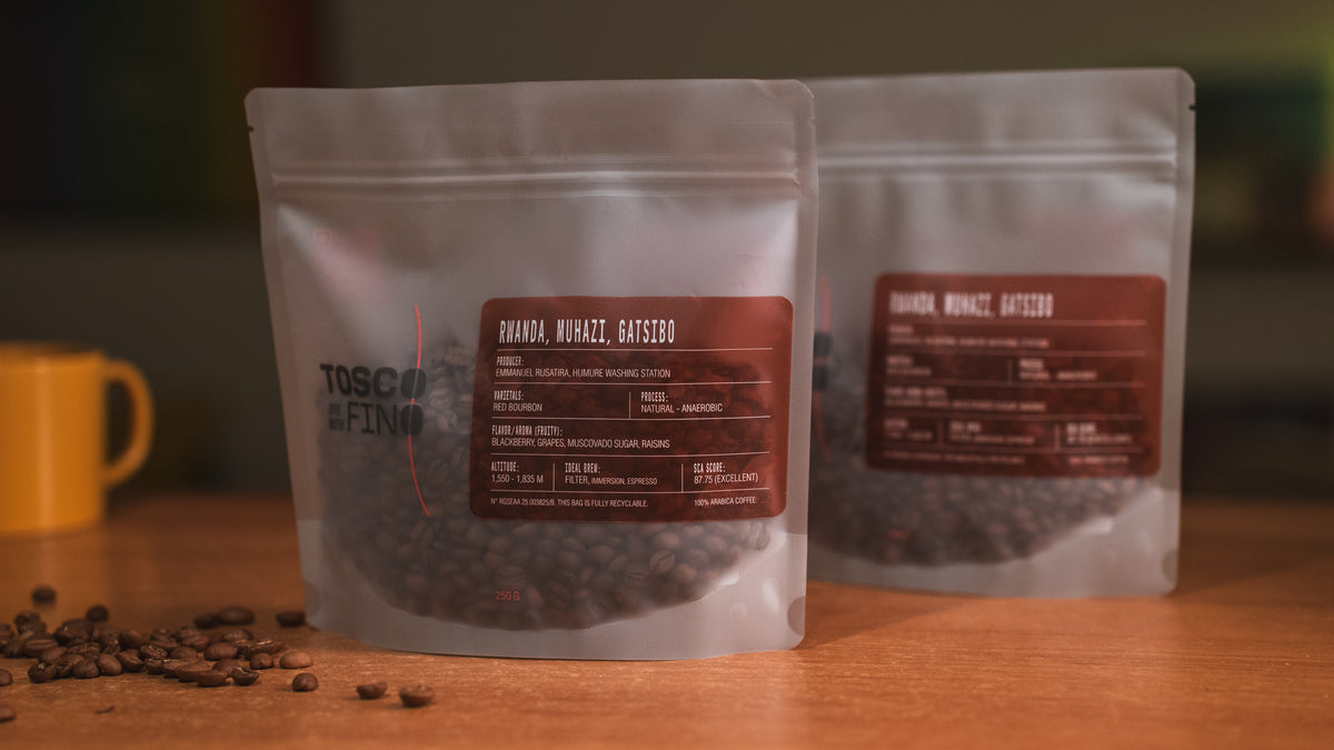 Two bags of Tosco Fino Rwanda Muhazi Gatsibo specialty coffee on a wooden café table