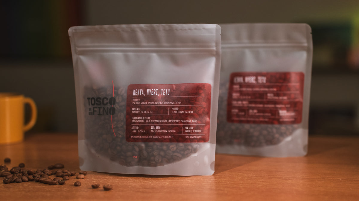 Two bags of Tosco Fino Kenya Nyeri Tetu specialty coffee on a wooden café table