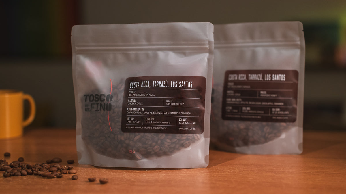 Two bags of Tosco Fino Costa Rica Tarrazú Los Santos specialty coffee on a wooden café table